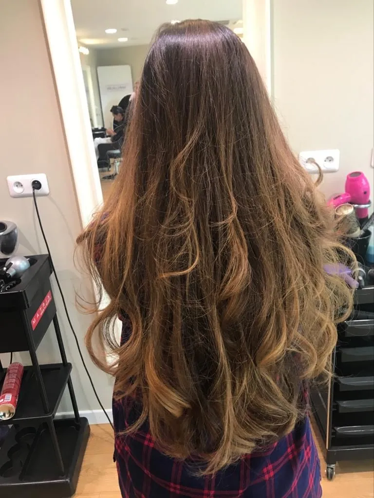 Chevelure longue et ondulée obtenue après une pose d'extensions complète